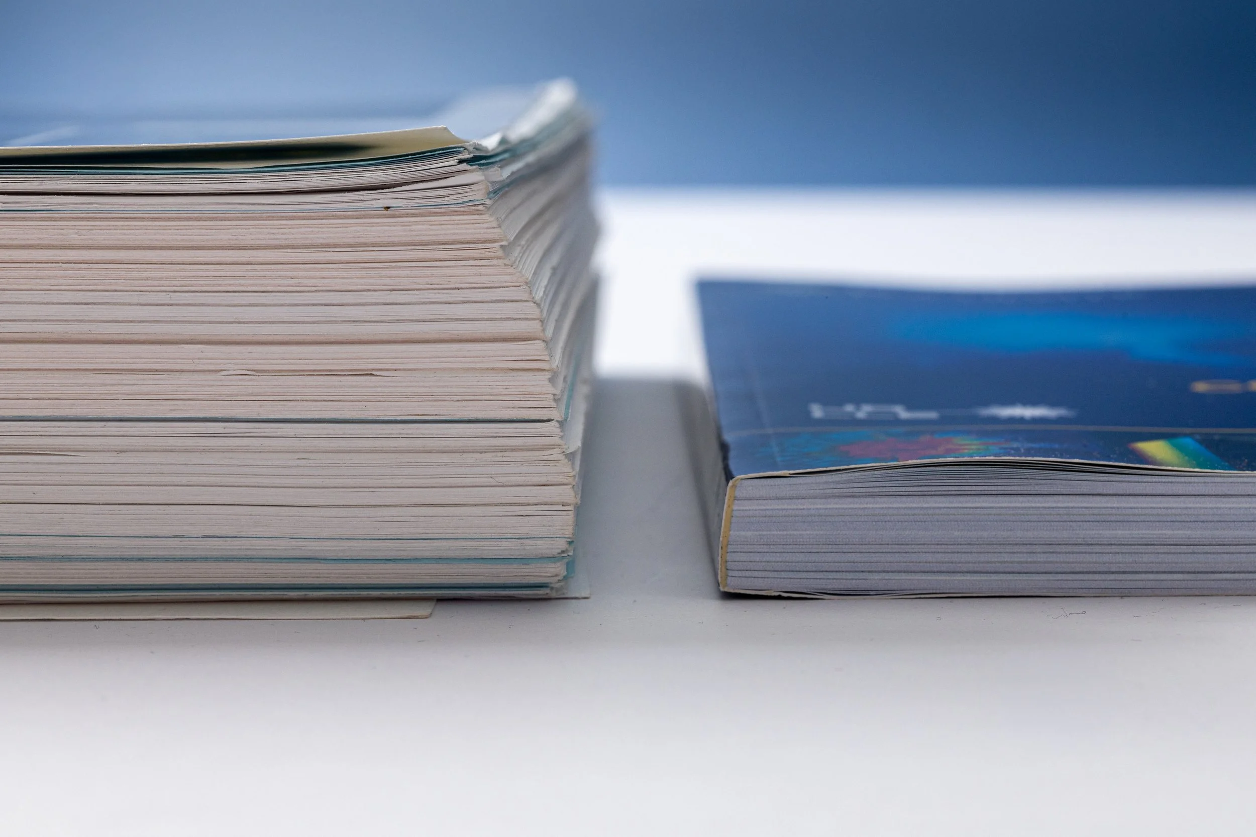 Two volumes, on the left, a several-inch thick document, and a much thinner and streamlined document on the right.