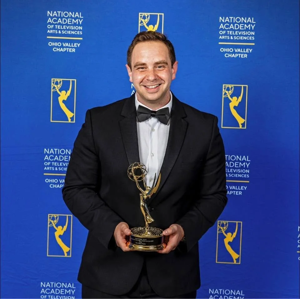 Austin Pollack in tuxedo holding an Emmy award in front of a backdrop with the text 'National Academy of Television Arts & Sciences Ohio Valley Chapter' and images of Emmy awards.