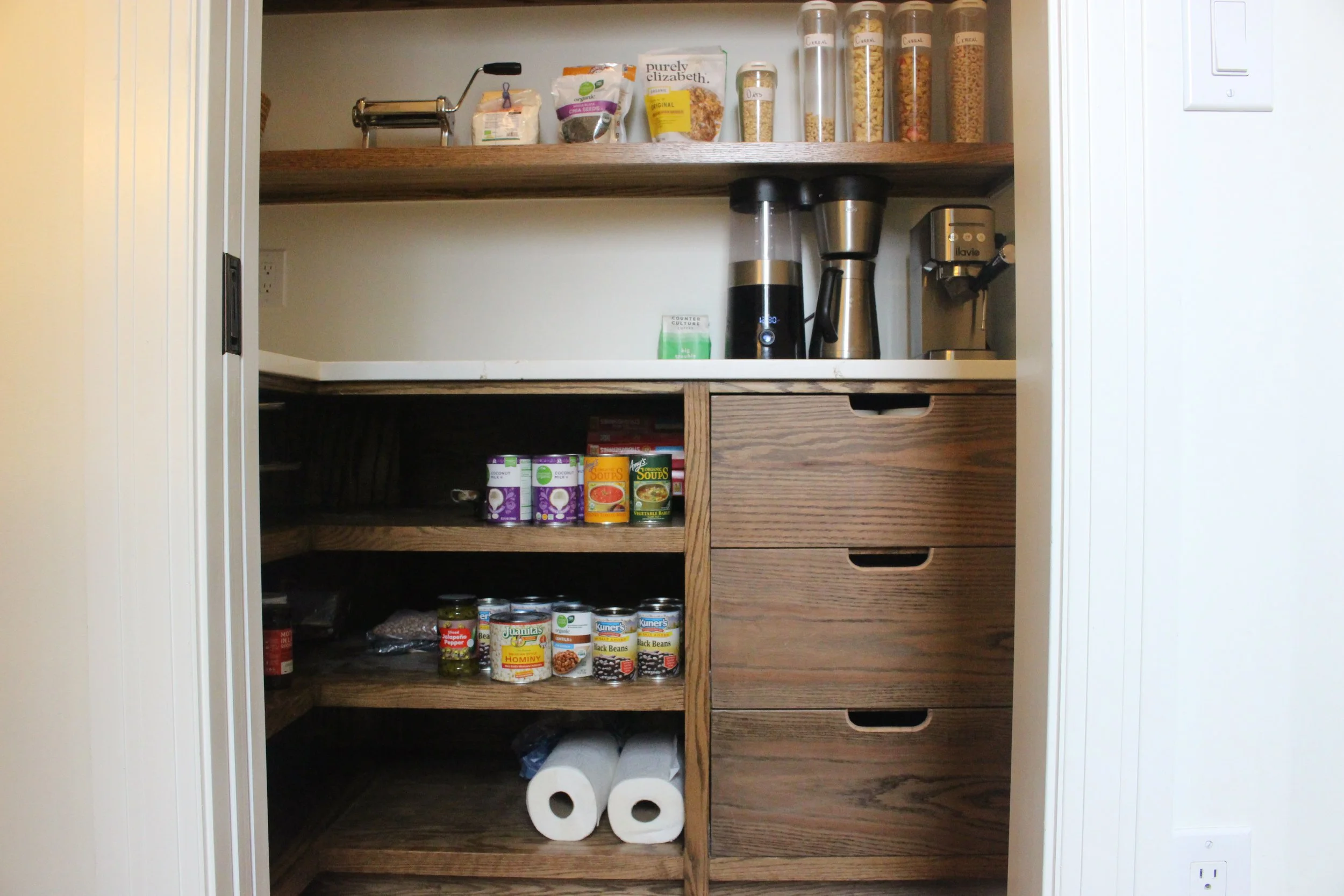 Pantry with shelves, drawers and a marble countertop.