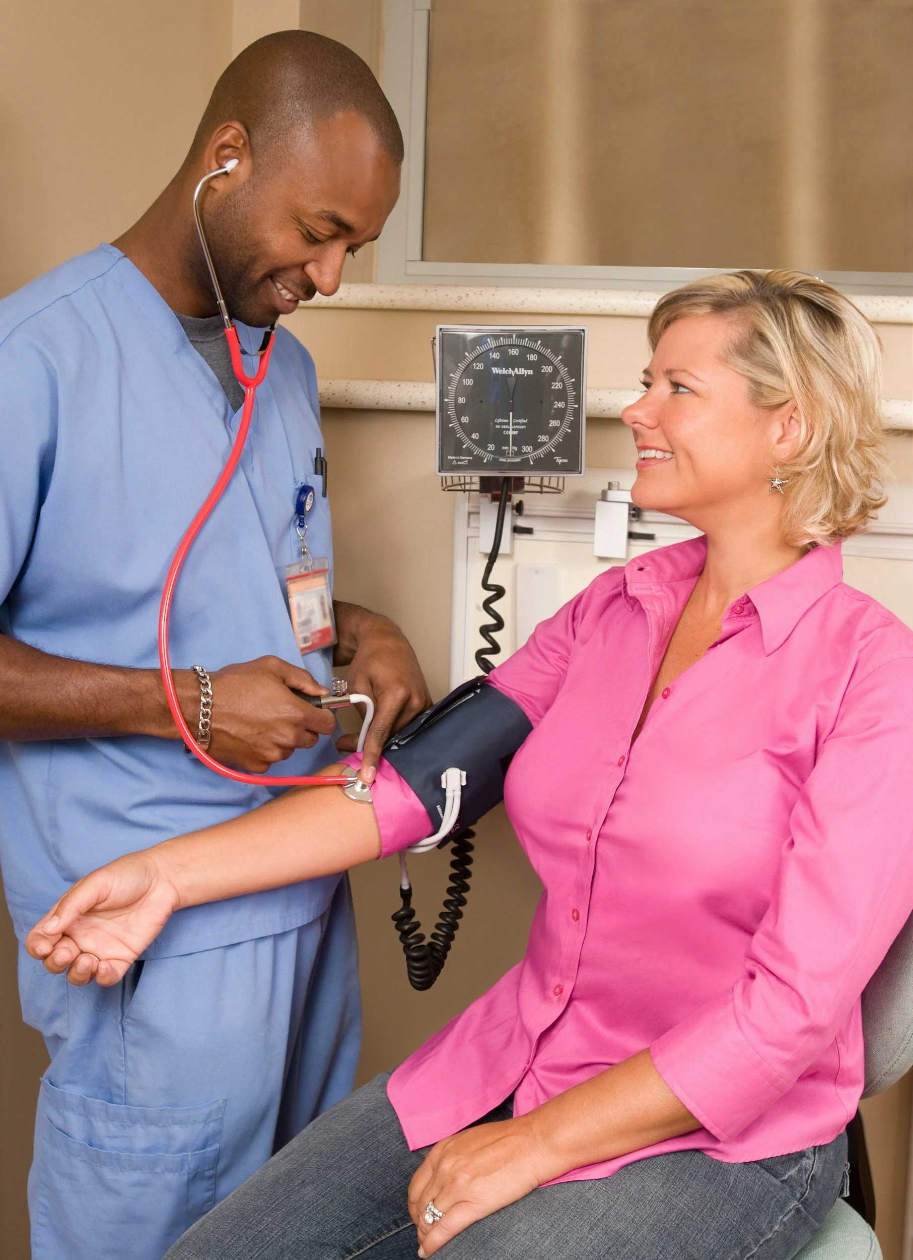 A nurse measuring a woman's blood pressure in a healthcare setting.