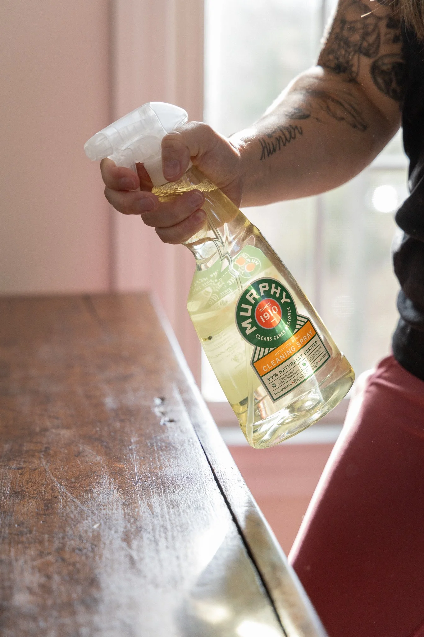 A person's hand holding a Wurphy cleaning spray bottle with a trigger spray top.