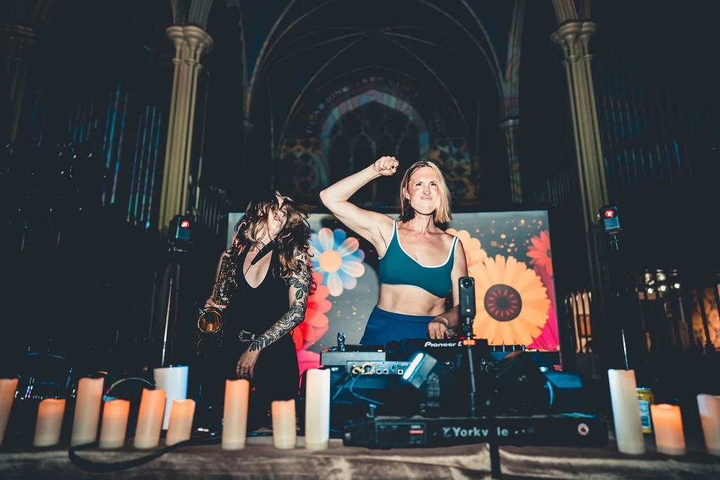 Rachel Molenda wearing blue cheerleading uniform performing and DJ-ing at REUNION Dance party event while she dances with friend