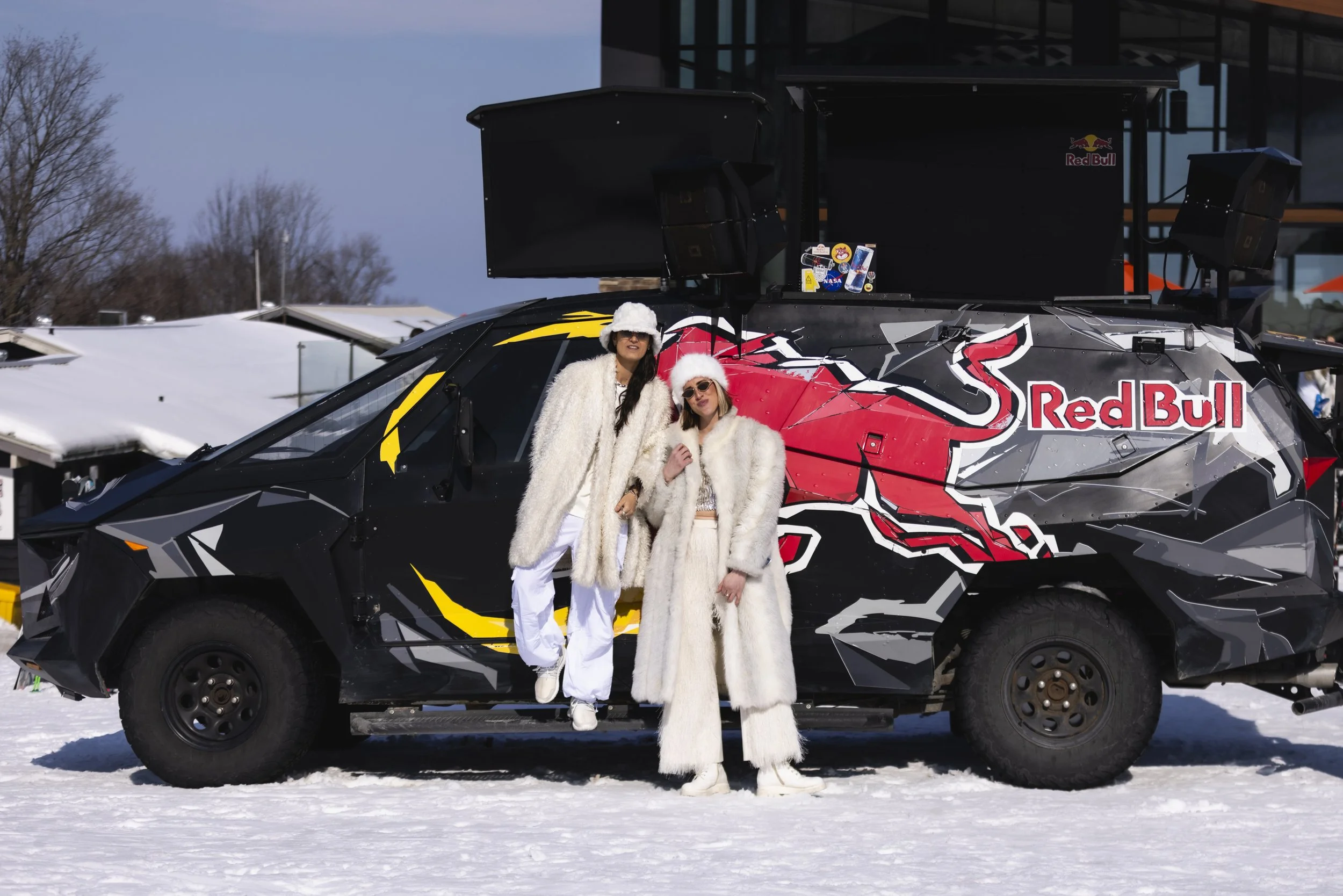 Rachel Molenda and friend wearing white fur outfit posing in front of Red Bull truck in the snow at Alpine Ski Resort event 