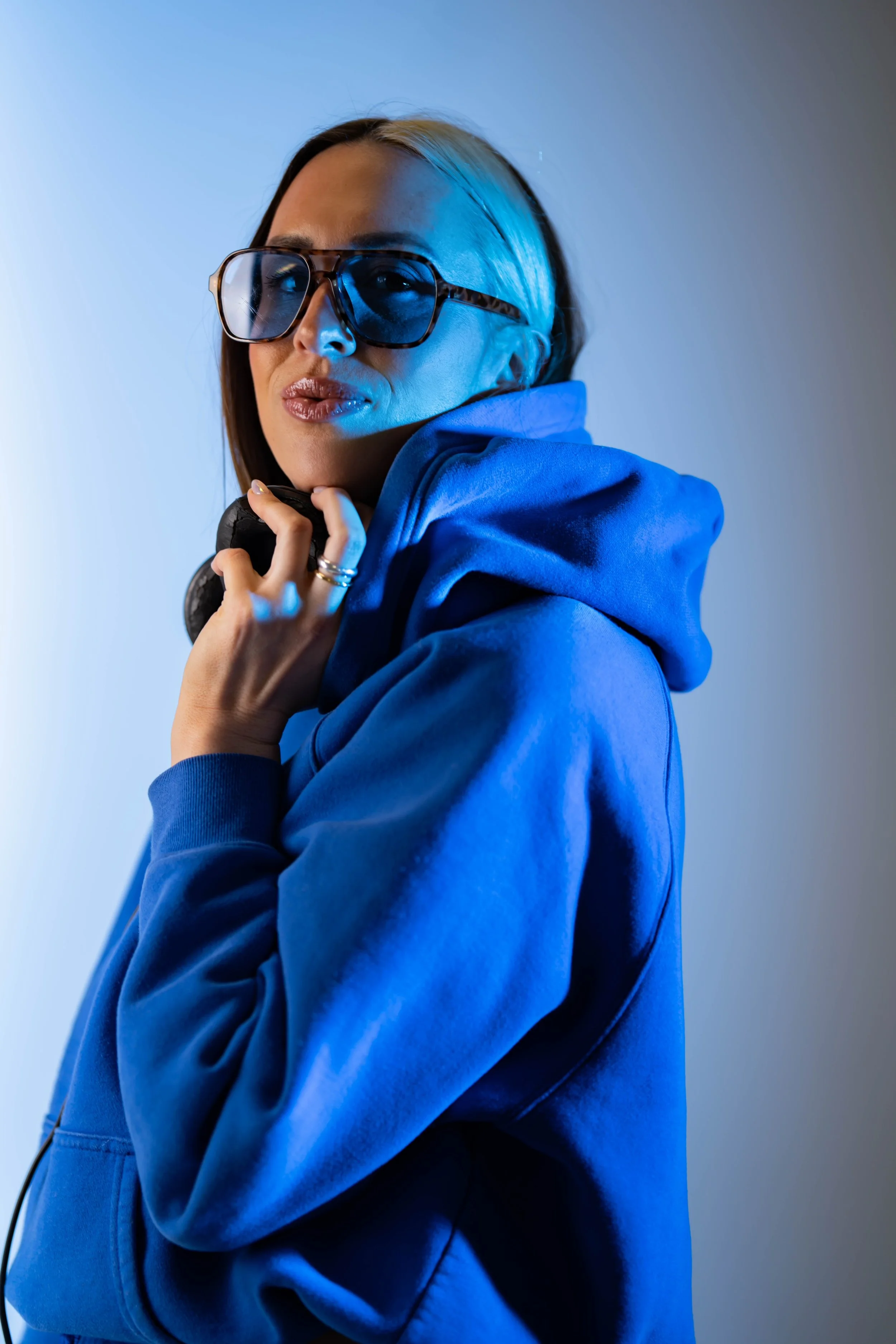 Rachel Molenda wearing blue sunglasses with a blue hoodie and DJ headphones on her head