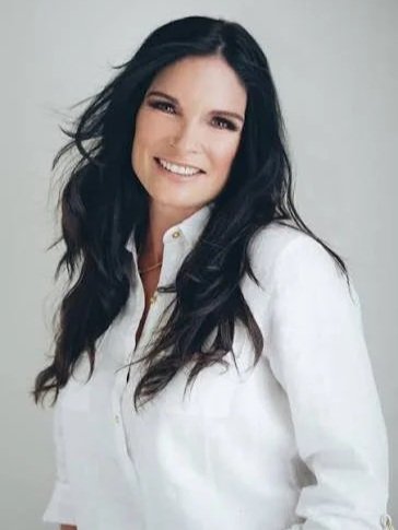 Debbie Sluys posing wearing a white button up shirt and smiling