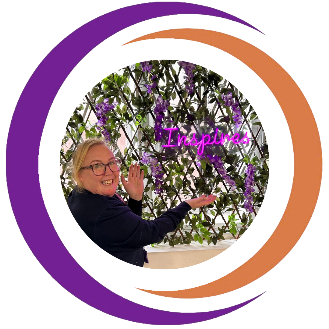 A woman wearing glasses and a dark jacket is smiling and posing with her hand raised near a purple-flowered plant. Behind her, there is a neon sign that reads "Inspires" in pink. The scene is framed with colorful, overlapping circular borders.