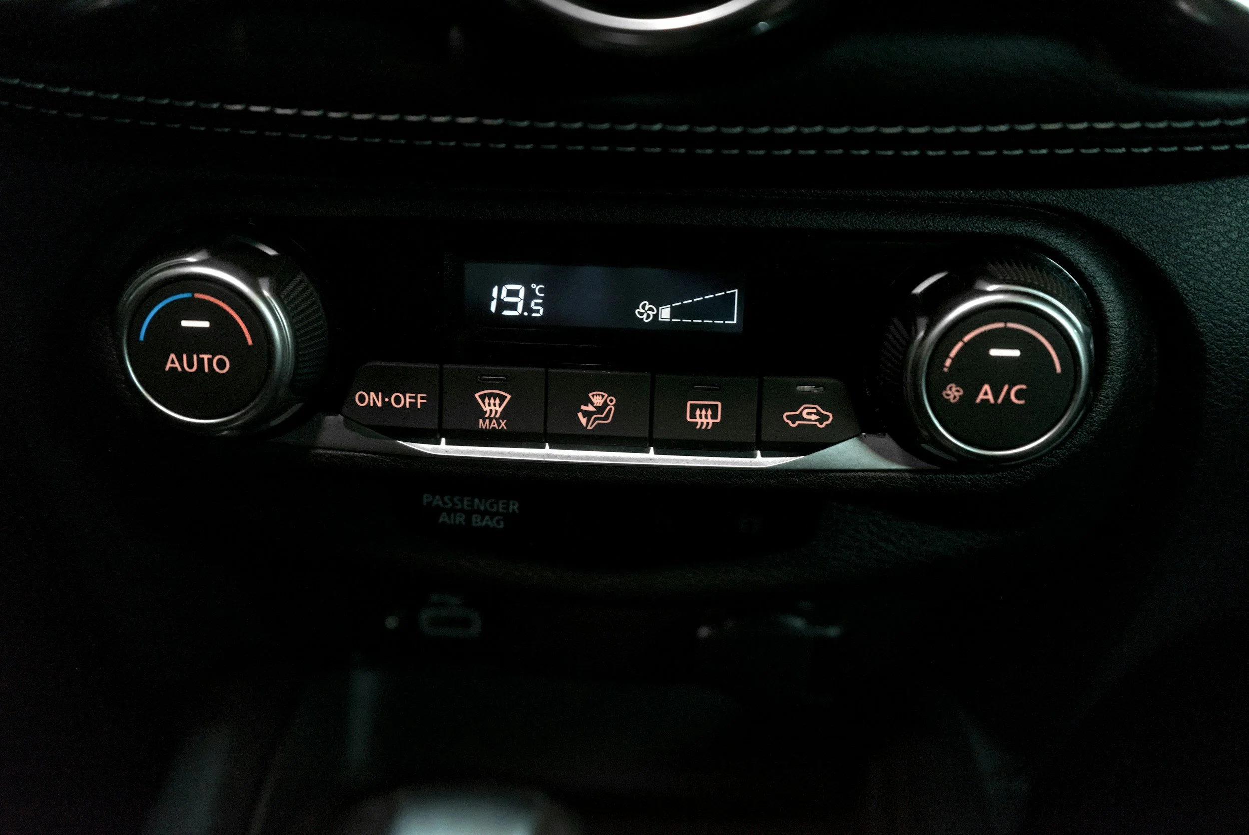 Car climate control panel with temperature set to 19.5°C, showing buttons for defrost, air circulation, and air conditioning.