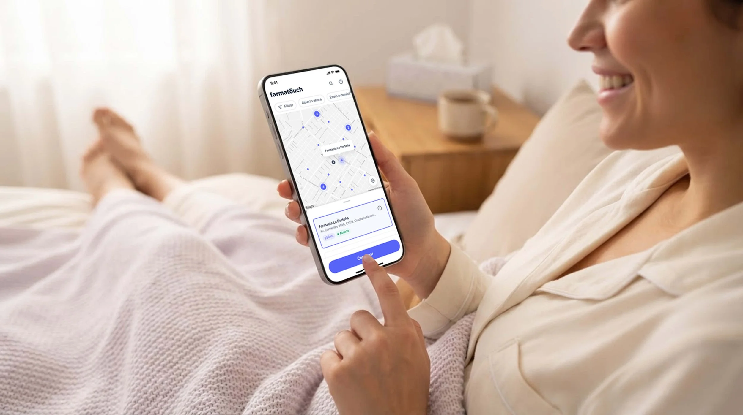 Woman relaxing in bed using the Farmatouch app on her phone to find a nearby open pharmacy on a map