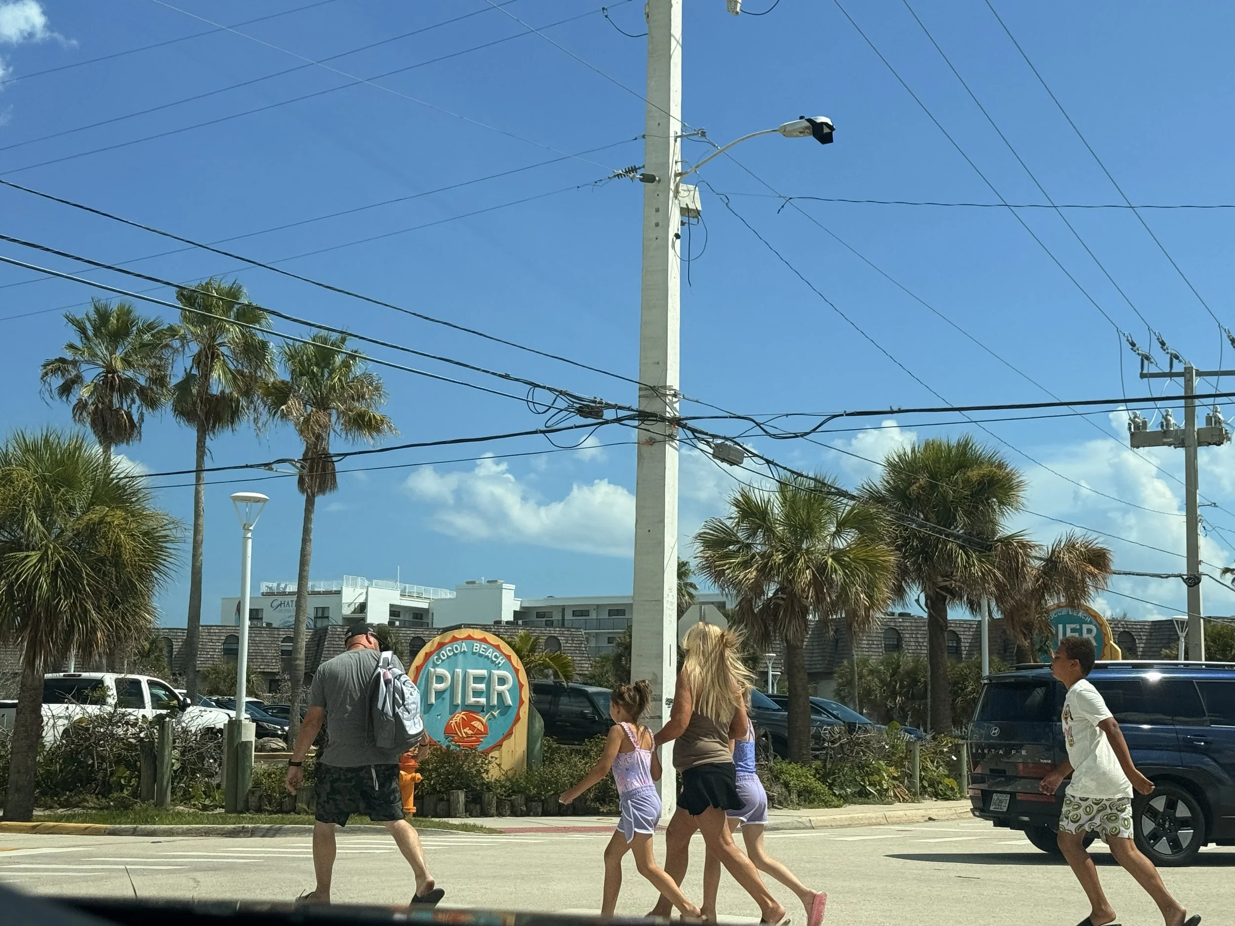 family of cruisers crossing the street to go to cocoa beach pier in cape canaveral florida
