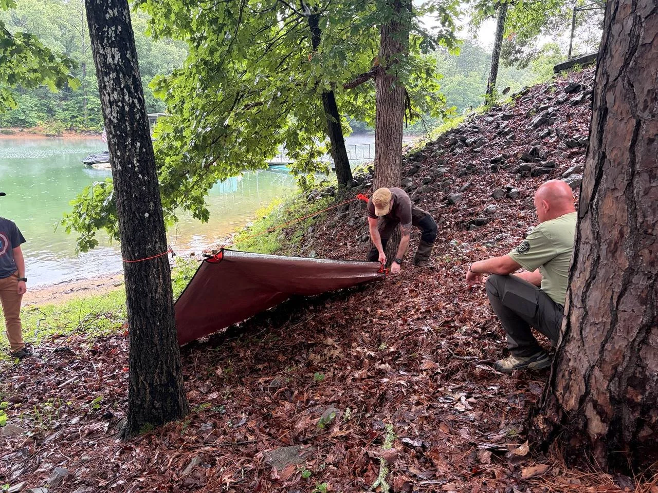 Kraken Combatives participants practicing tarp shelter setup beside the lake.