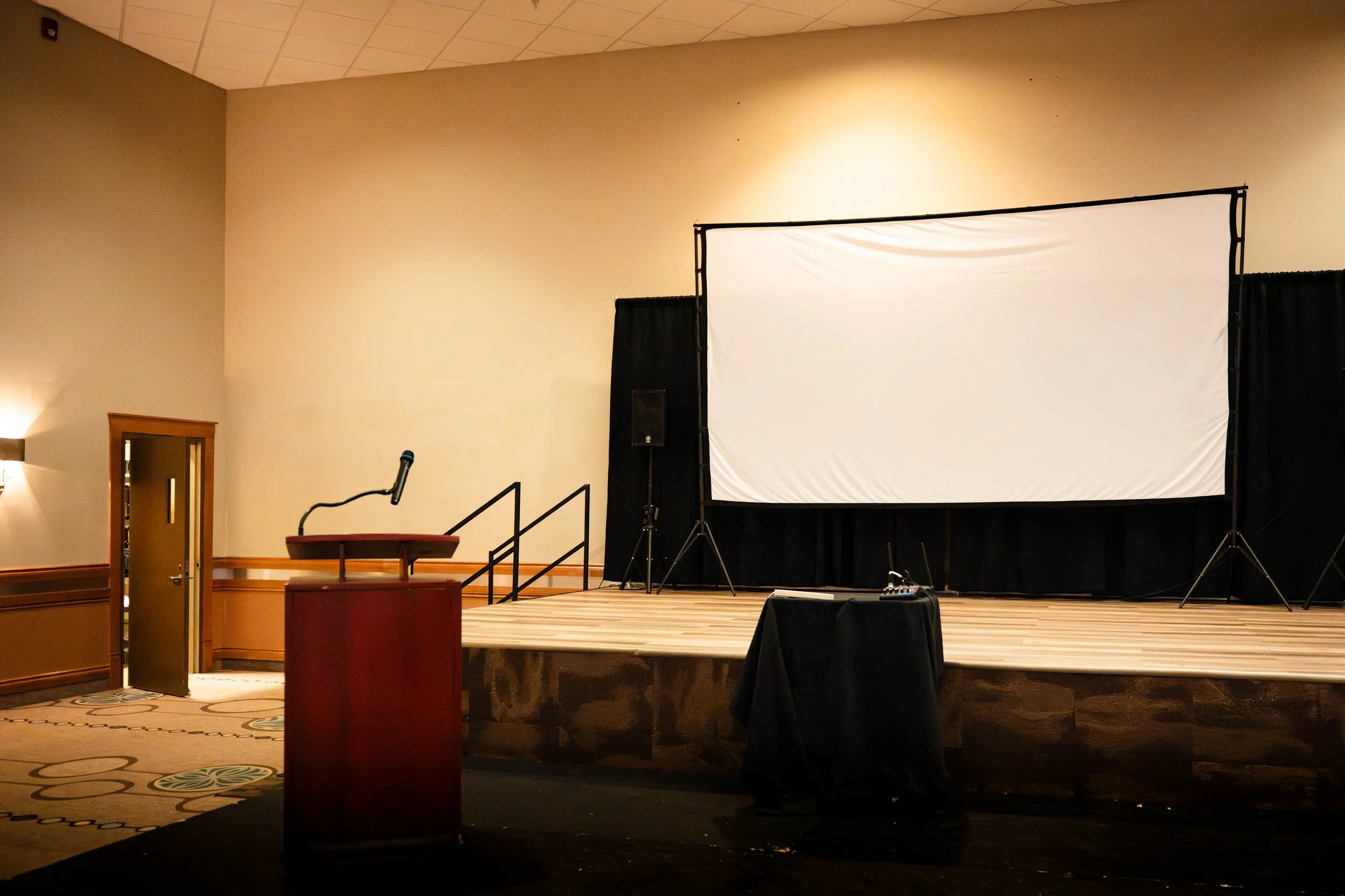 a stage with a podium in a ballroom at the Best Western Plus Rose Country Hotel