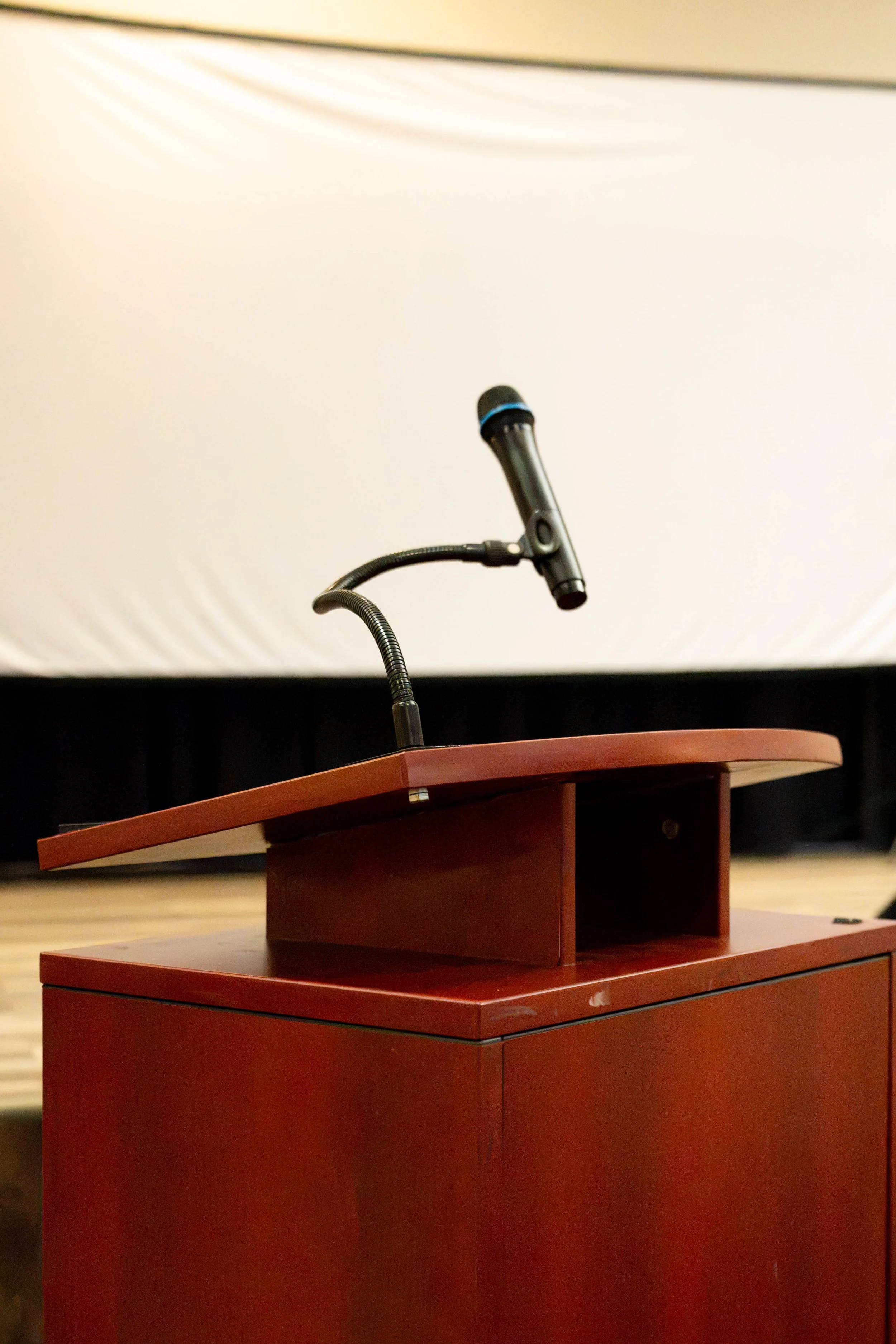 Podium with a microphone inside a banquet room for meetings and events