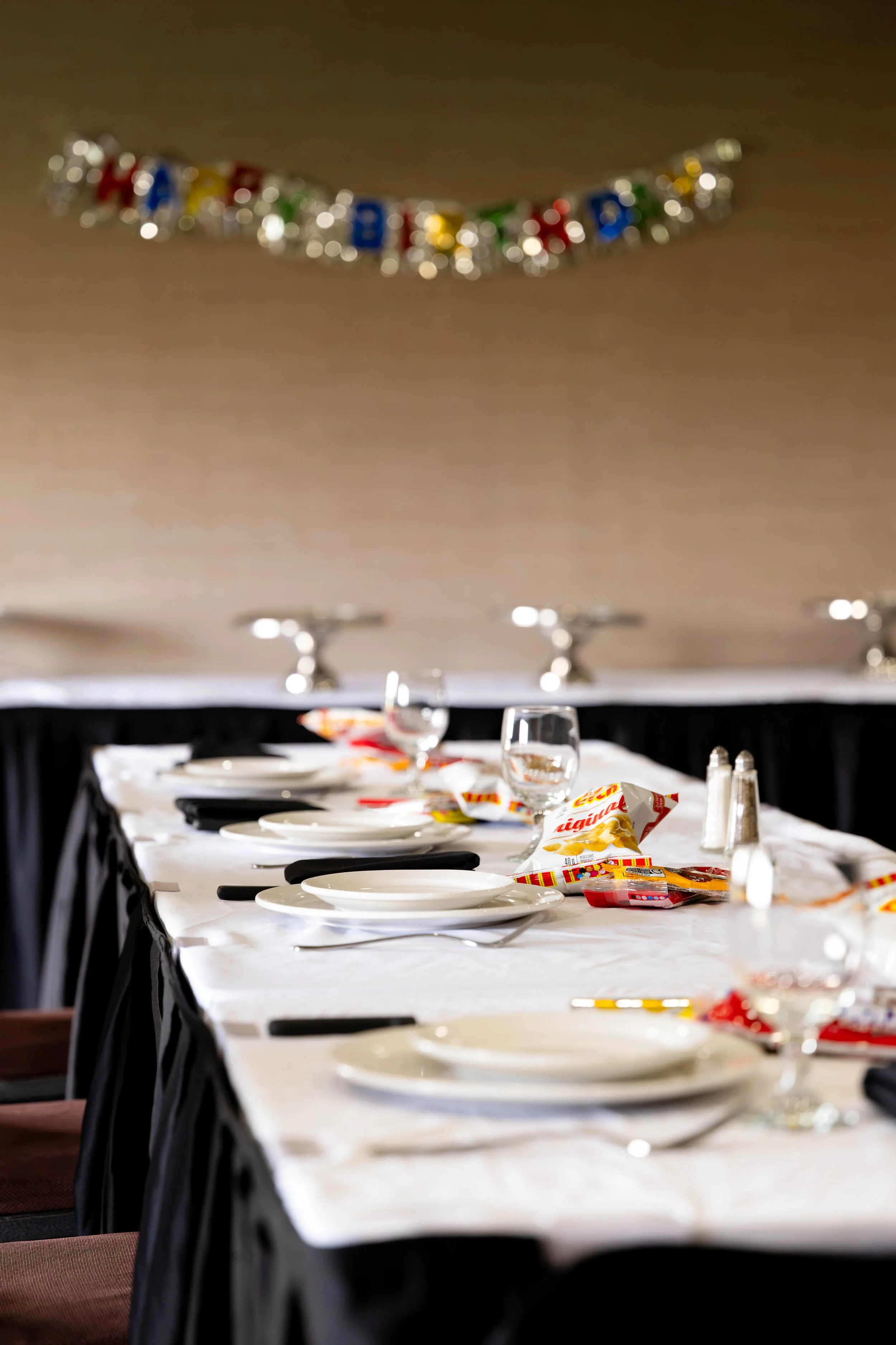 harvest room set up for a social event with plates, glasses and chips on the table