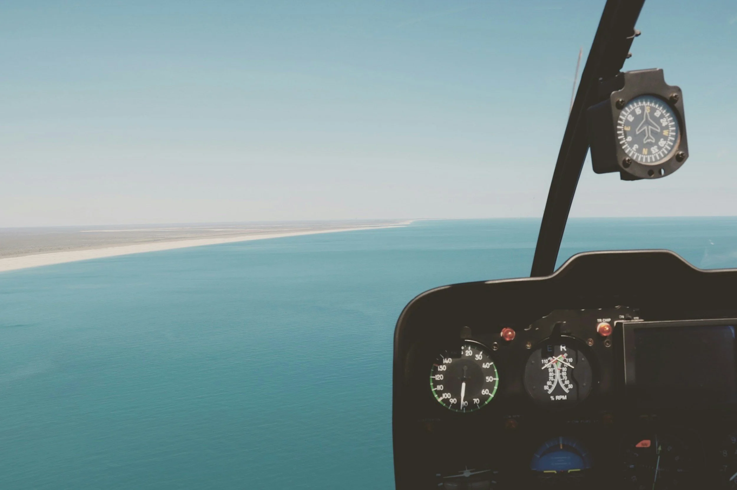 Pilotens Instrumententafel mit Ozean und Küste im Hintergrund, Blick aus dem Cockpit eines Flugzeugs.