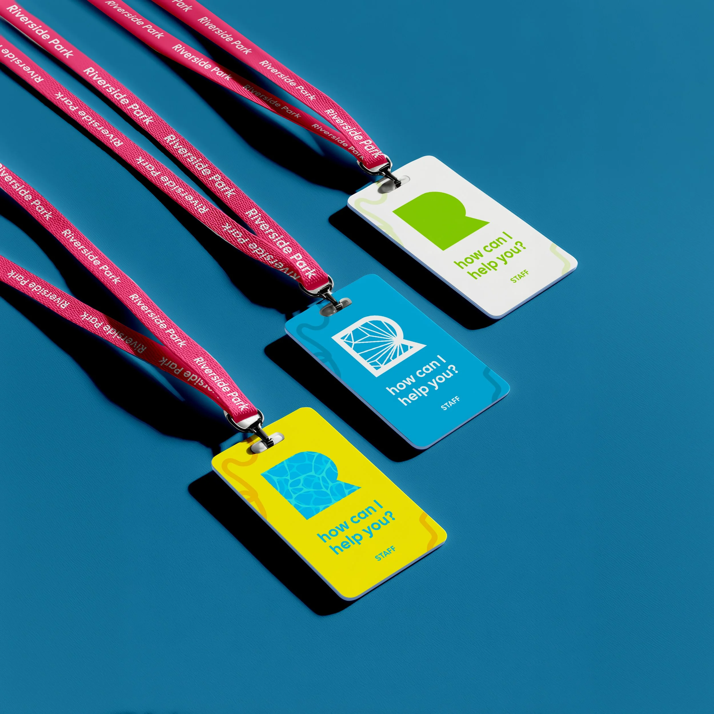 Colorful cards with questions and staff labels, each attached to a lanyard with 'Riverside Park' written on it, laid out on a blue surface.