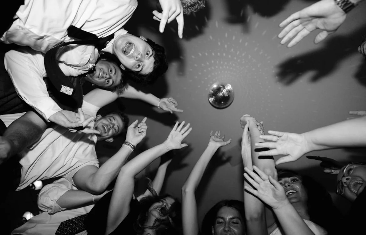 Group of people at a party reaching for a disco ball with excited expressions