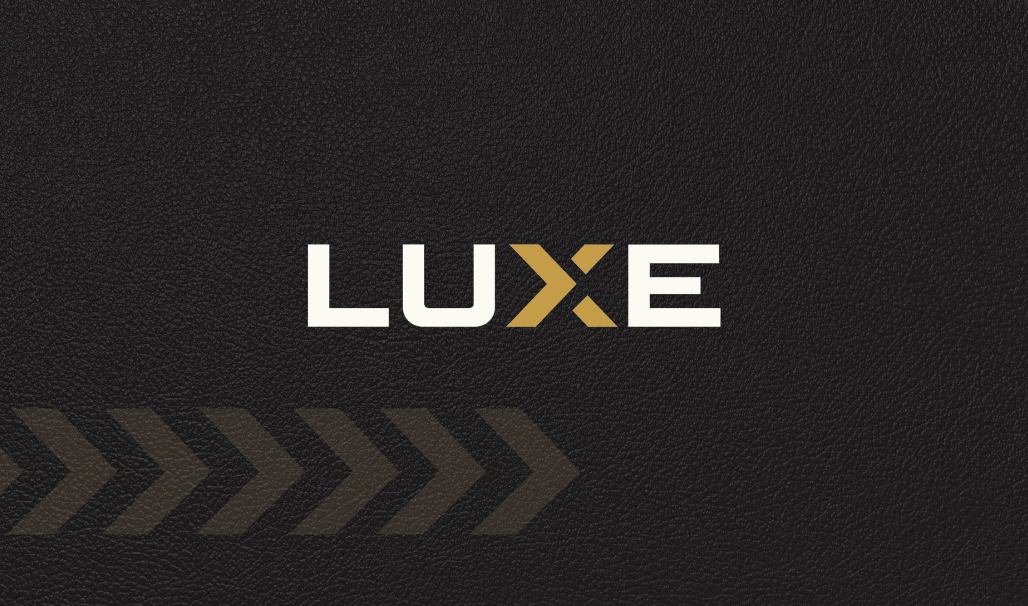 Black textured background with the word 'LUXE' in white and gold letters and a series of dark gold chevrons pointing right.