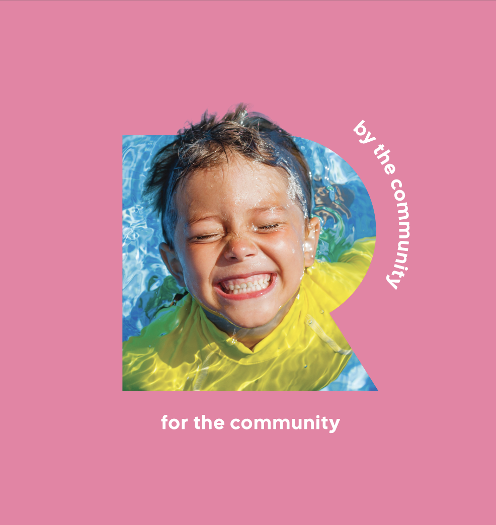 A smiling young boy with wet hair in a pool, wearing a yellow shirt, on a pink background with white text that says 'by the community for the community'.