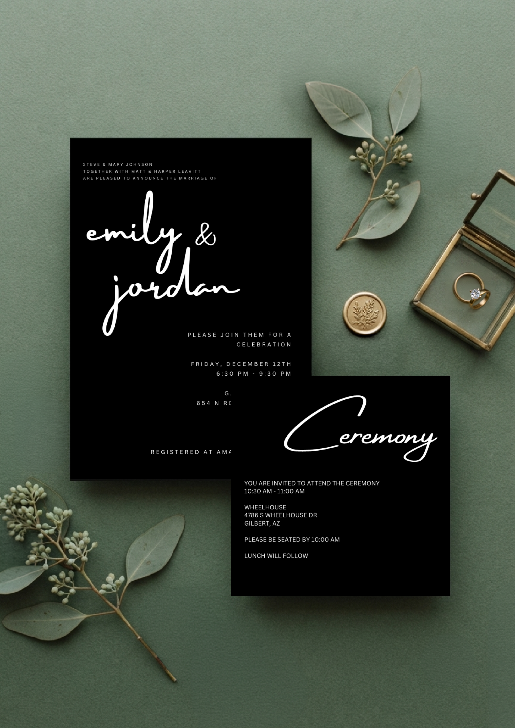 Wedding invitation card with black background and white handwritten style text, surrounded by greenery, leaves, and jewelry, on a green textured surface.
