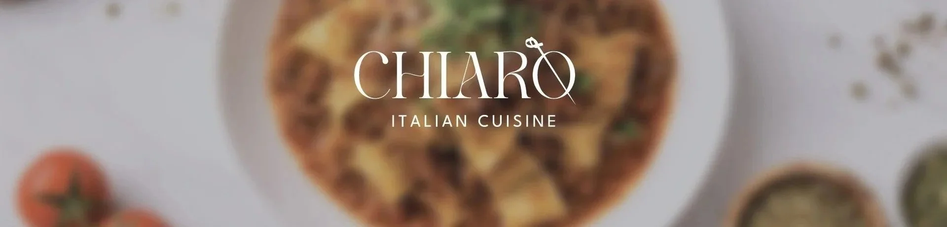 Blurry image of a pizza with toppings, along with tomatoes and herbs on a white plate, with the text 'Chiaro Italian Cuisine' overlaid.