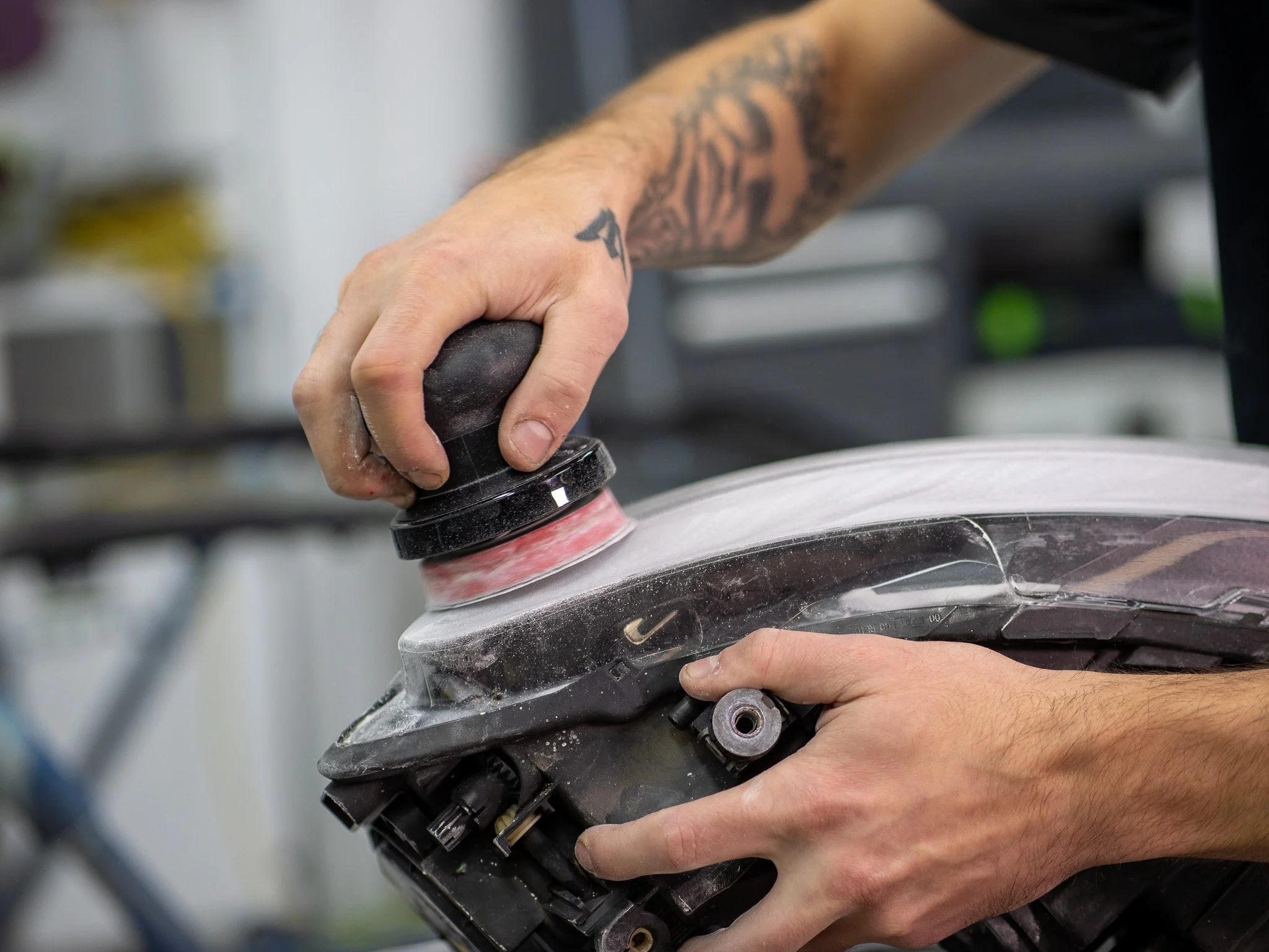 Person hält ein elektronisches Gerät in den Händen, das wahrscheinlich ein Motor oder eine Maschine ist und an eine Werkbank oder eine Werkstatt angebracht ist.