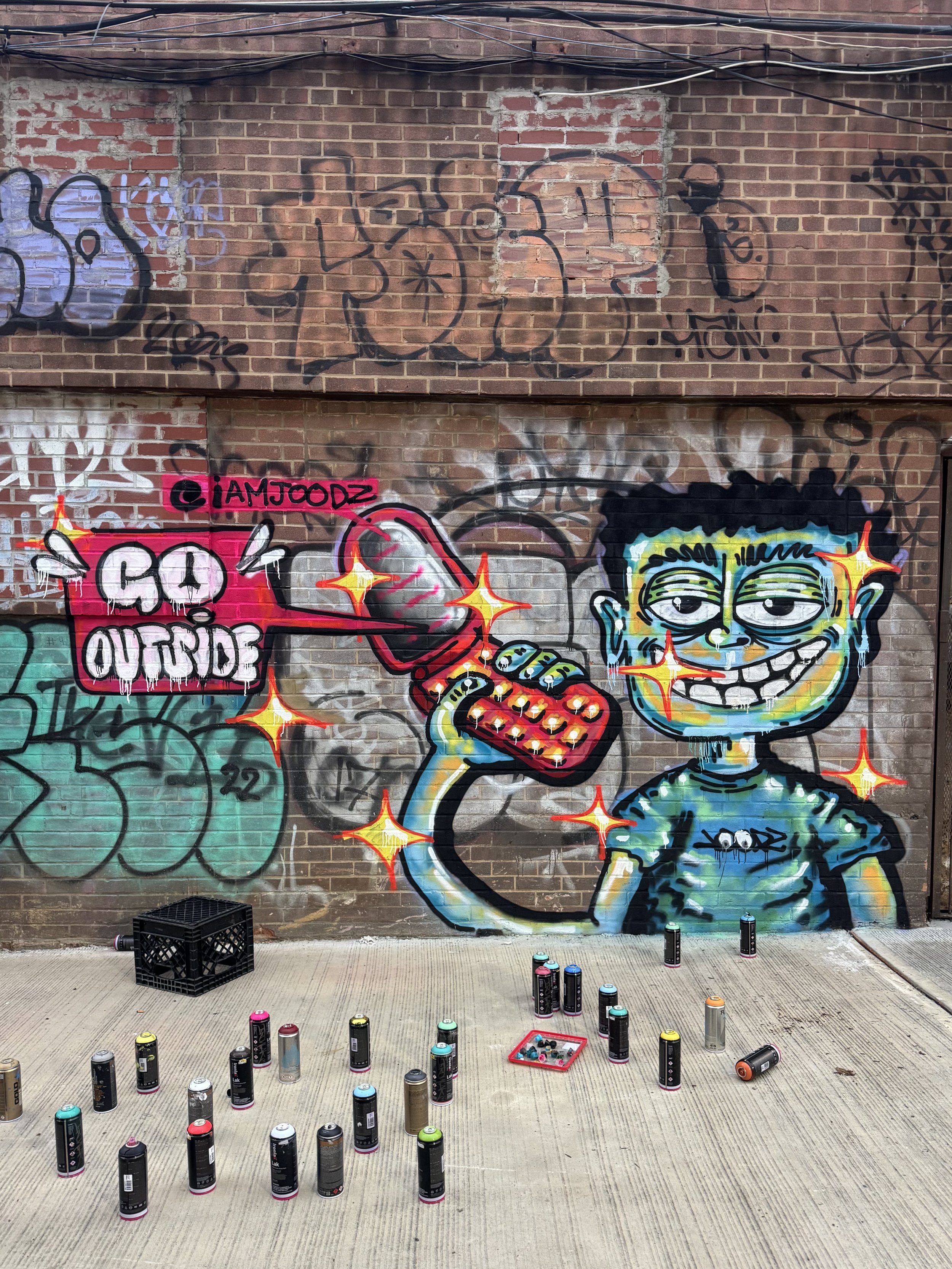 Go Outside street art mural by IAMJOODZ featuring a colorful character holding a heart with graffiti lettering.