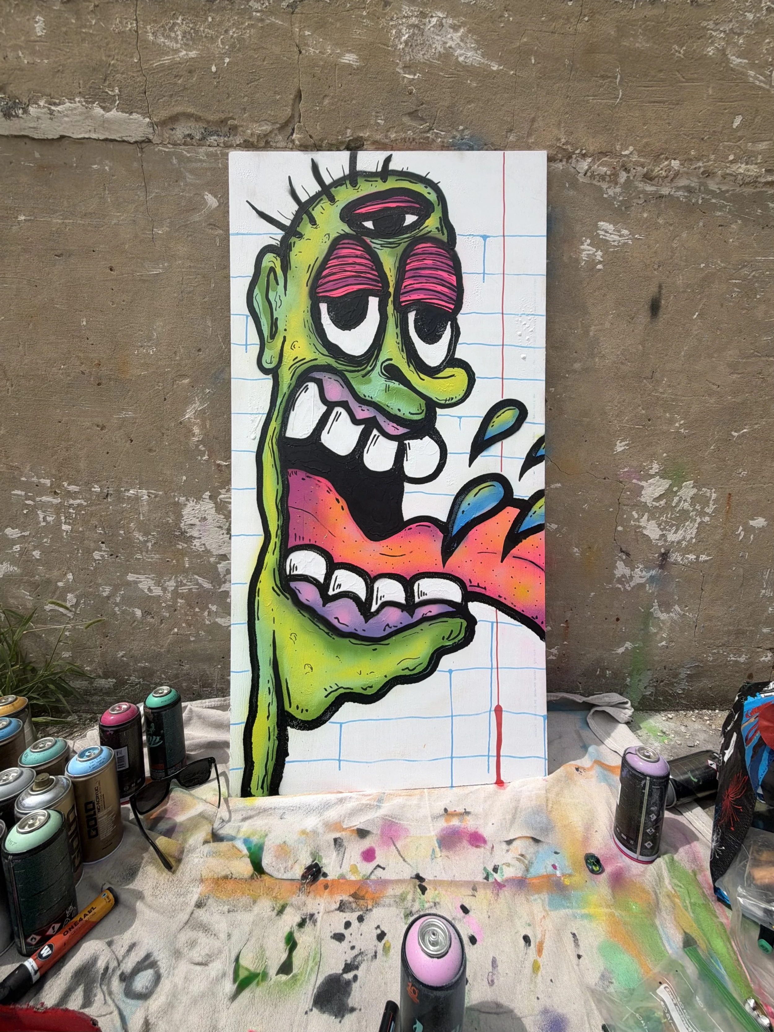 Three-eyed green character canvas artwork by IAMJOODZ featuring vibrant pink, orange and blue details.