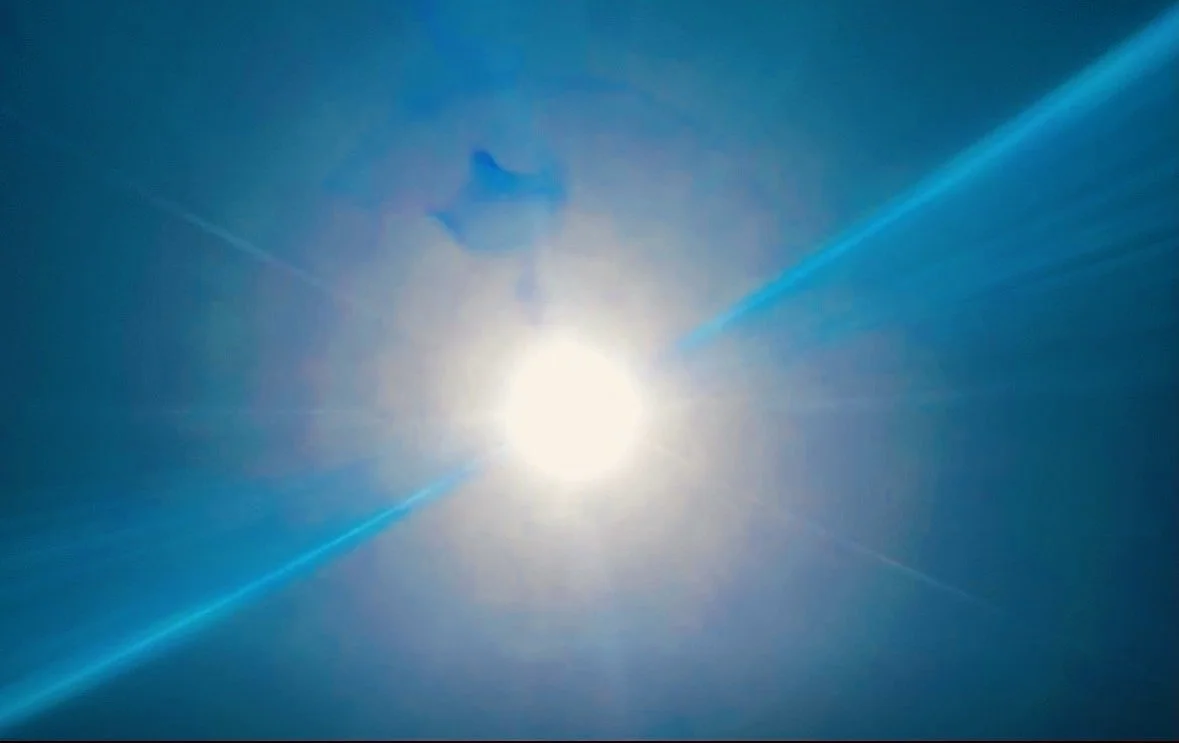 Bright sun shining in a clear blue sky with sun rays and lens flare effects, creating streaks of light on the Q Strategy Group Website