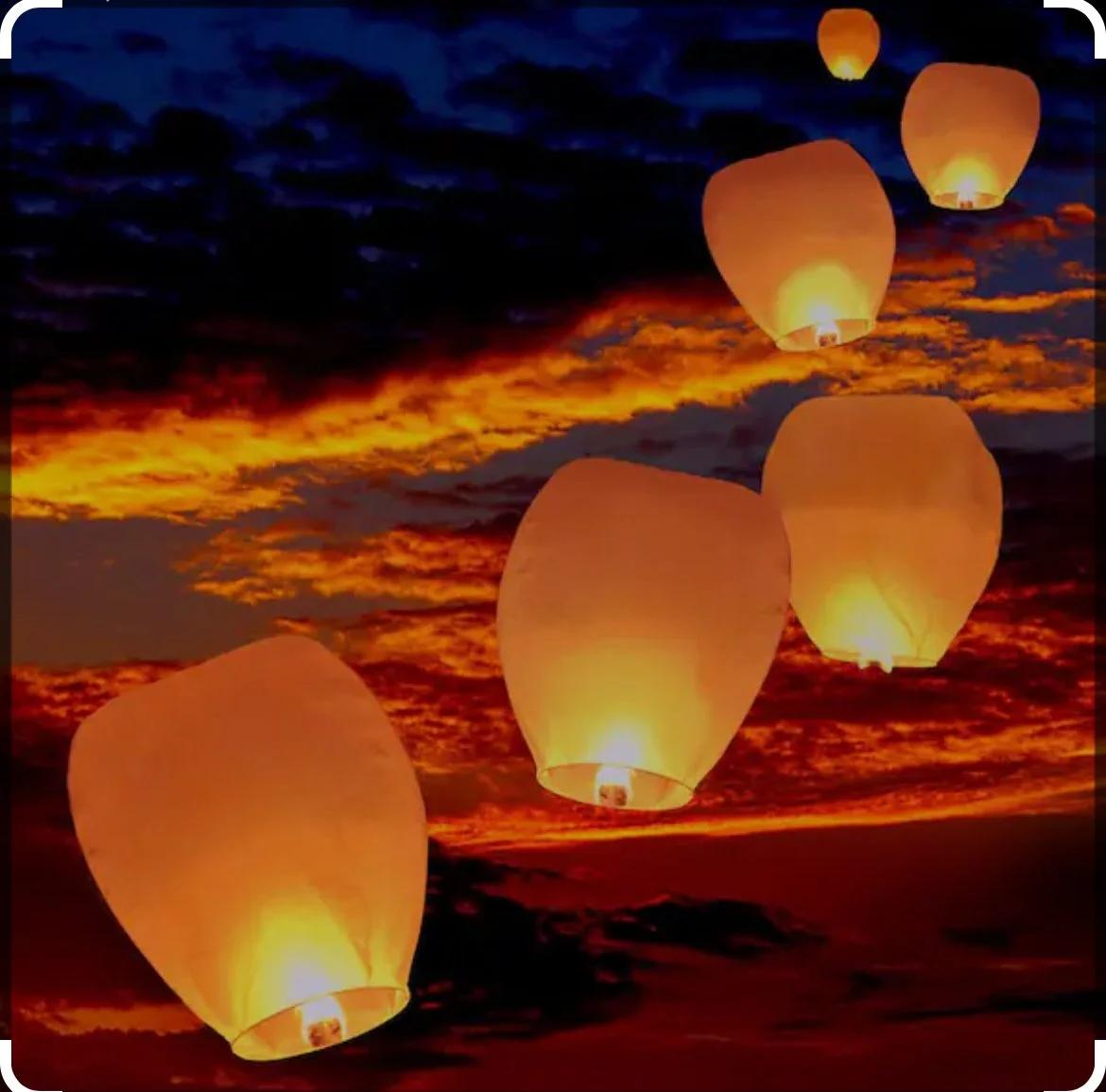 Sky lanterns floating against a colorful sunset sky with dark clouds on the Q Strategy Group Website