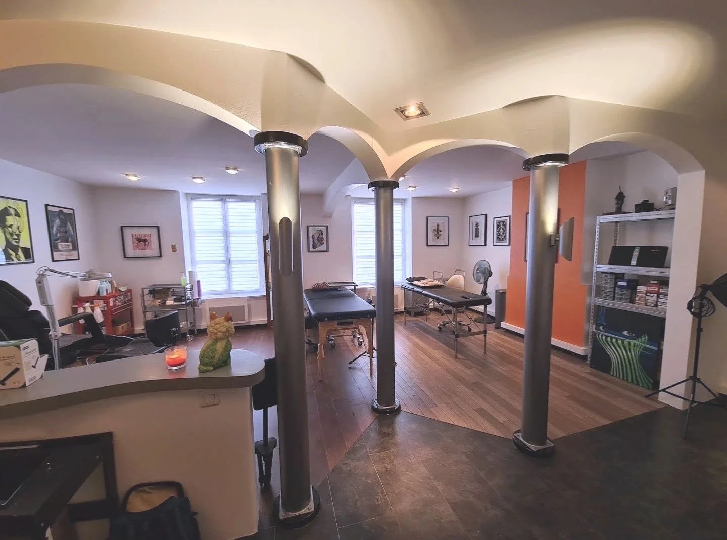 Salon de tatouage privé et cosy à Nancy, baigné de lumière naturelle, avec des colonnes métalliques et des panneaux de bois sombre. Expérience unique pour les amateurs de tatouages couleur et personnalisés en Lorraine.