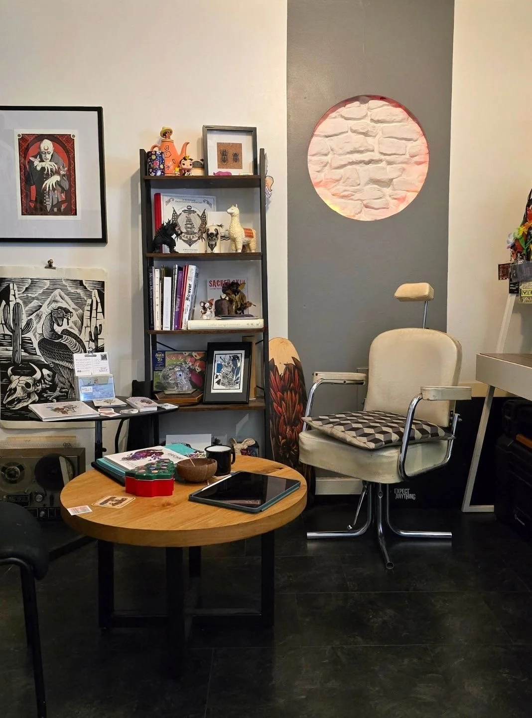 Salle d'attente et bureau cosy de notre salon de tatouage à Nancy. Espace décoré avec un mobilier varié et des œuvres murales originales, créant une ambiance agréable pour les clients avant leur séance. Salon de tatouage en Lorraine.