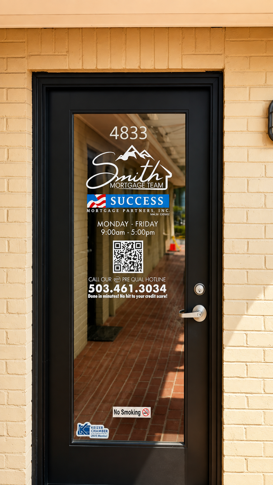 Glass door with business hours and contact information for Smith Mortgage Team, including a QR code, no smoking sign, and Keizer Chamber sticker. The door is set in a light yellow brick wall.