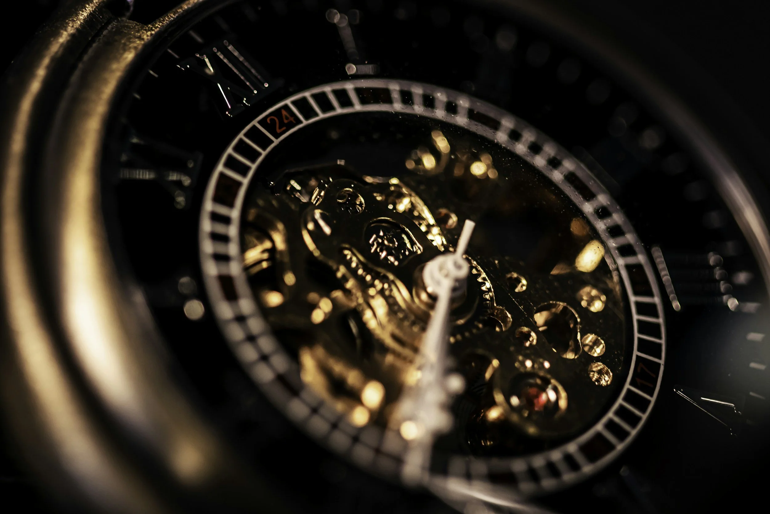 Close-up of a mechanical watch's internal gears and a partially visible dial with a 24-hour indicator.