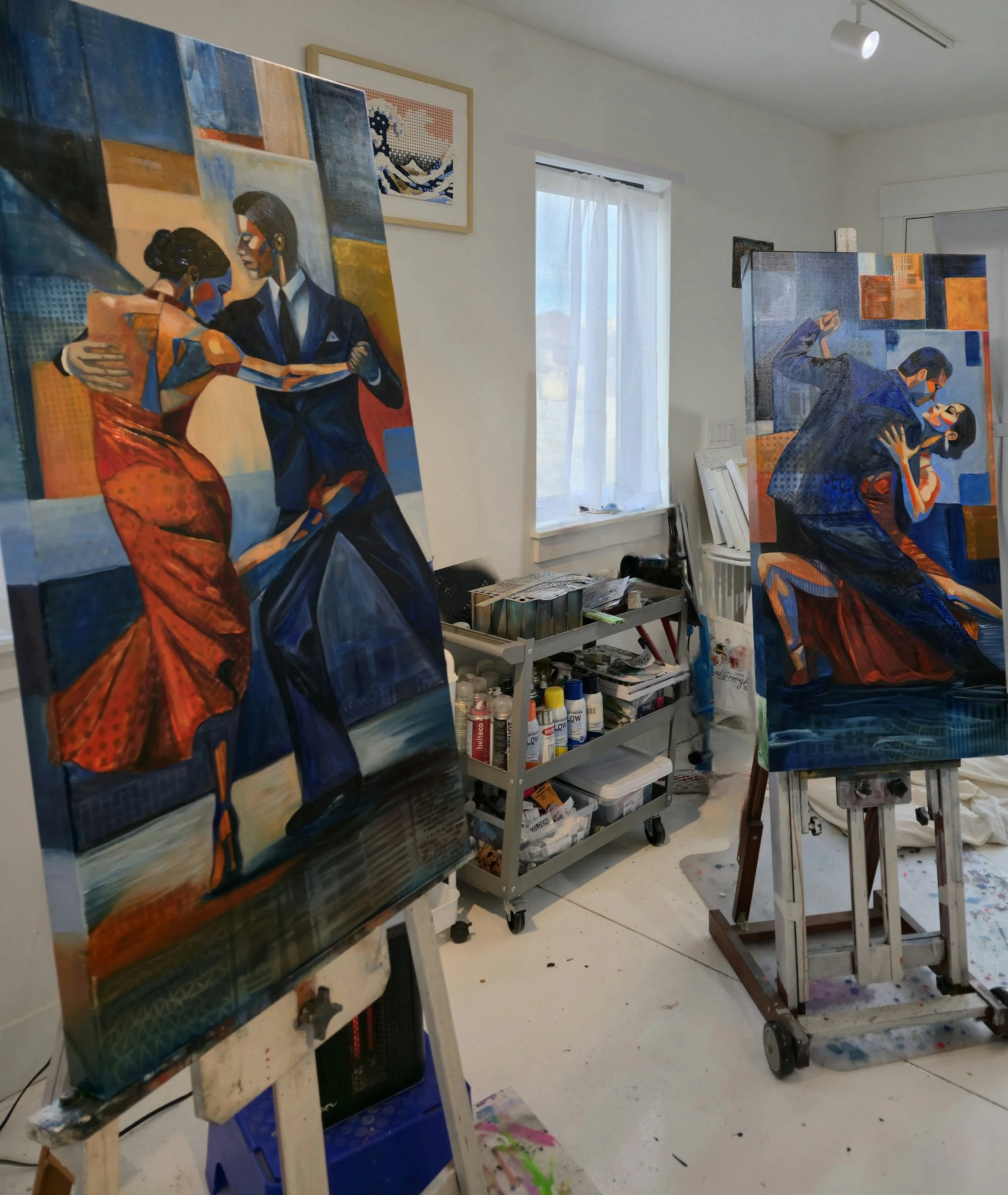 An art studio with several completed paintings on easels and a cart with art supplies, paint bottles, and brushes. One painting depicts a couple dancing, with a woman in a red dress and a man in a suit.
