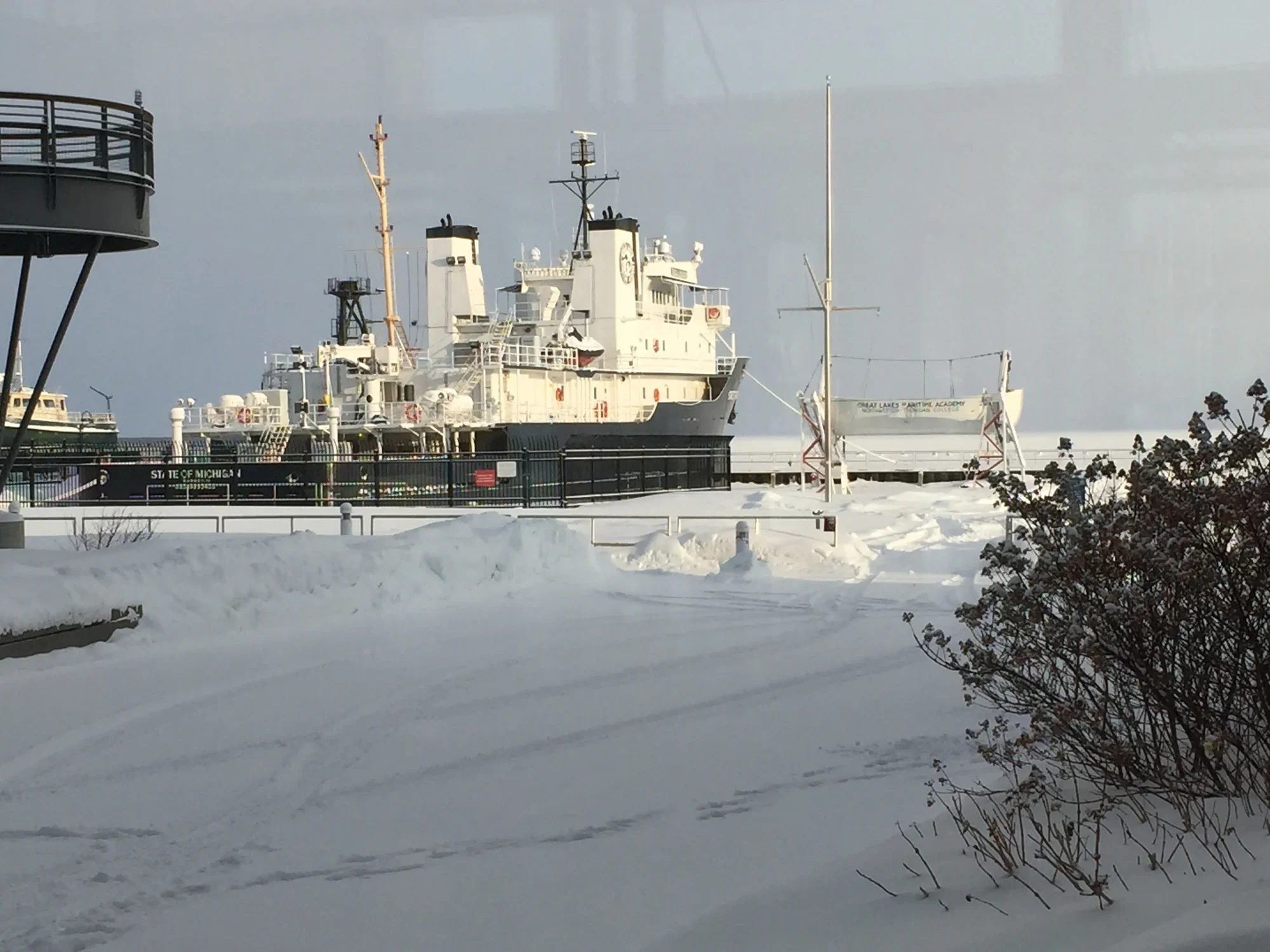 Frozen harbor keeping the State of Michigan, NMC's teaching ship at dock, snow-covered ground, and cloudy sky.