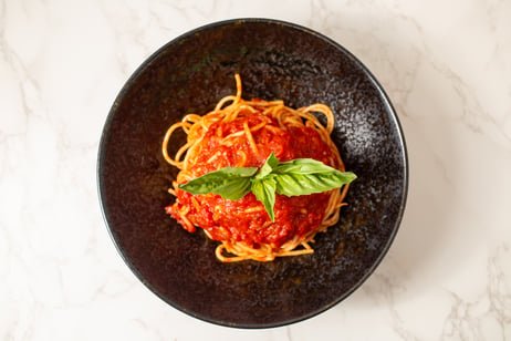 Plate of spaghetti topped with tomato sauce and fresh basil leaves