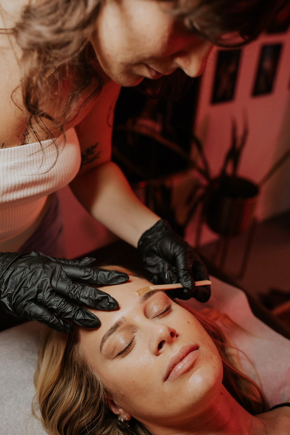 Close-up of an esthetician performing an eyebrow waxing service on a client