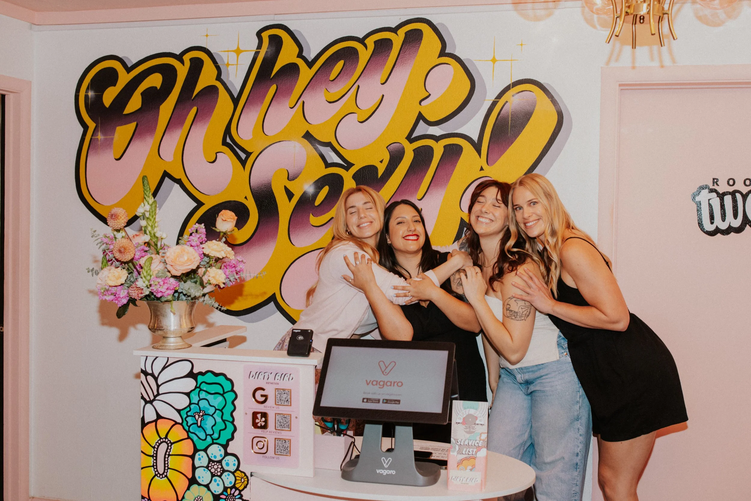 Waxing studio team smiling together at the front desk of Dirty Bird Esthetics