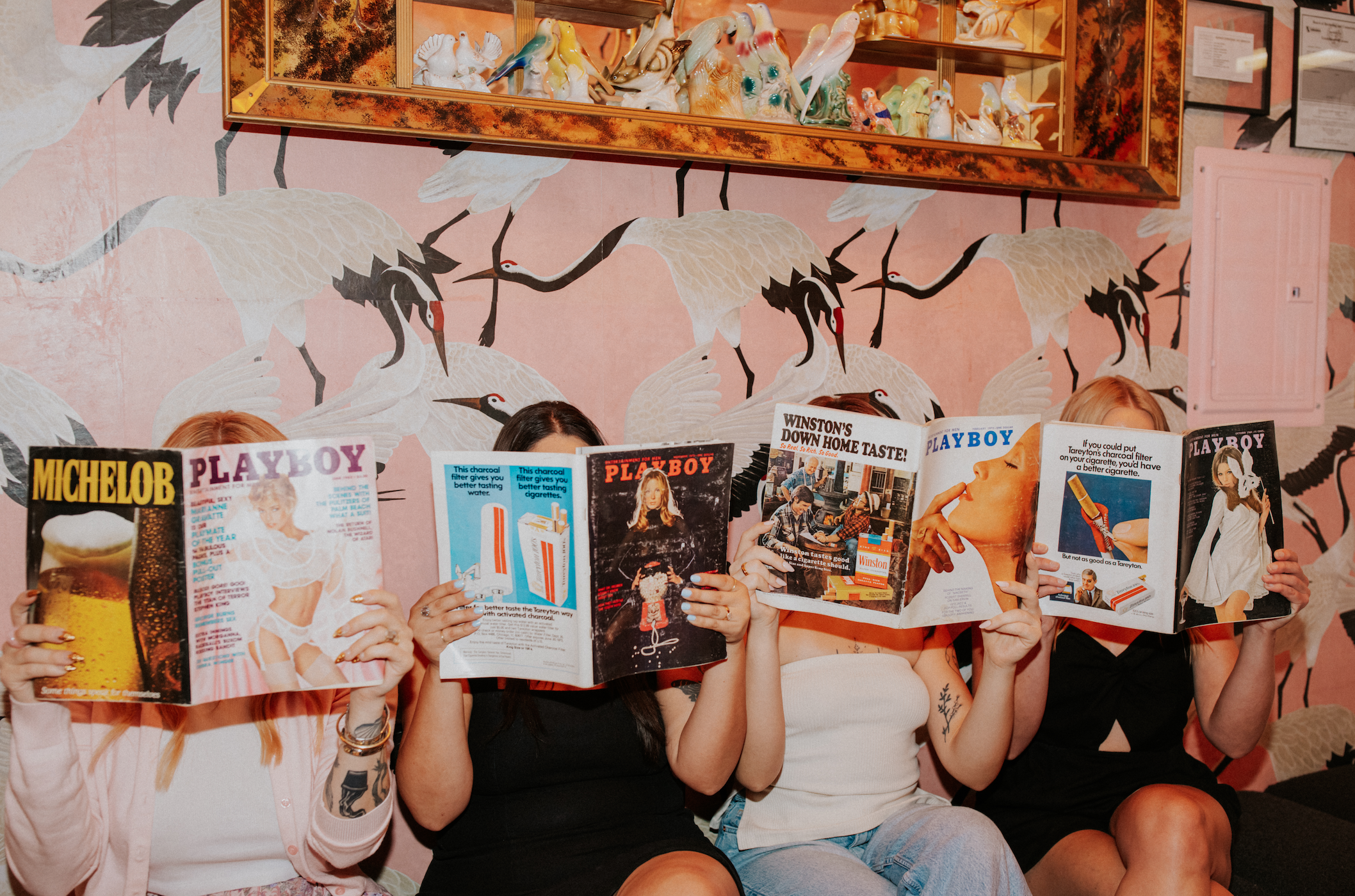 Waxing studio team members posing with vintage magazines in a retro-inspired studio