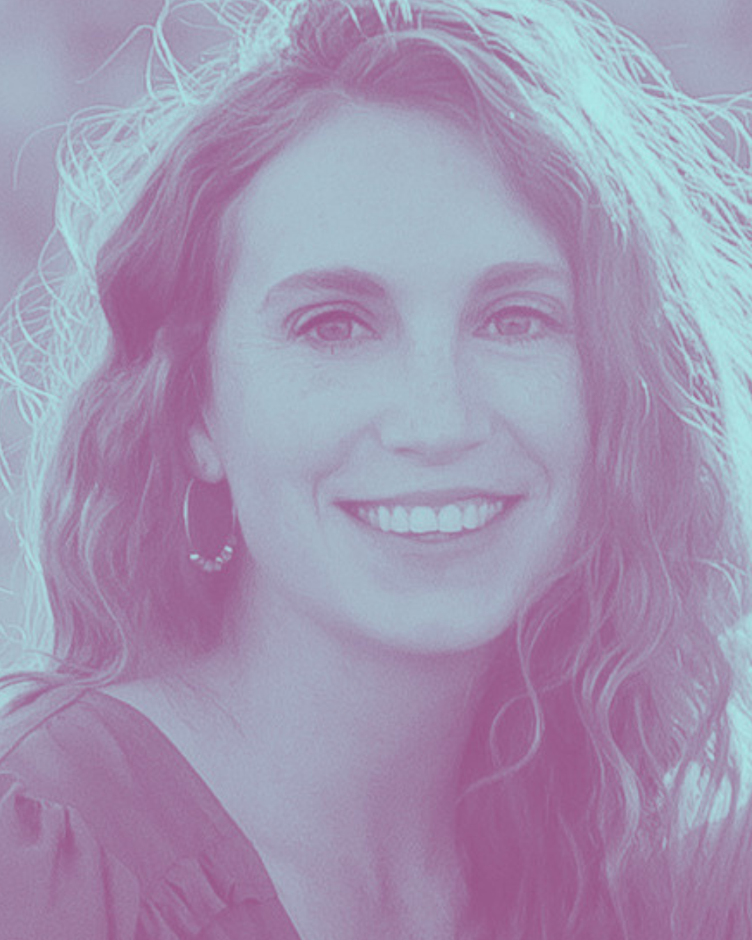 A woman with long, wavy hair smiling outdoors.