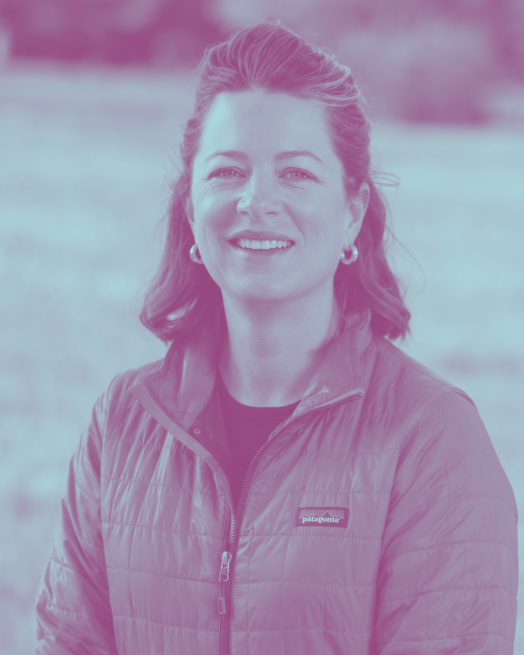 Smiling woman outdoors wearing a Patagonia jacket with a blurred natural background.