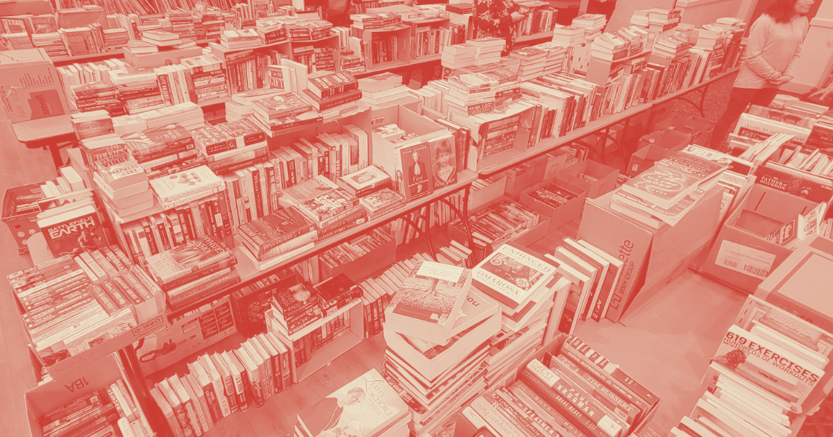 A densely packed book sale or bookstore with tables and shelves filled with books.