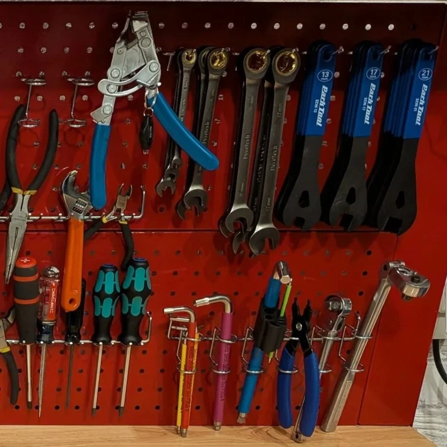 A red tool board holding various hand tools including wrenches, pliers, screwdrivers, and cutting tools.