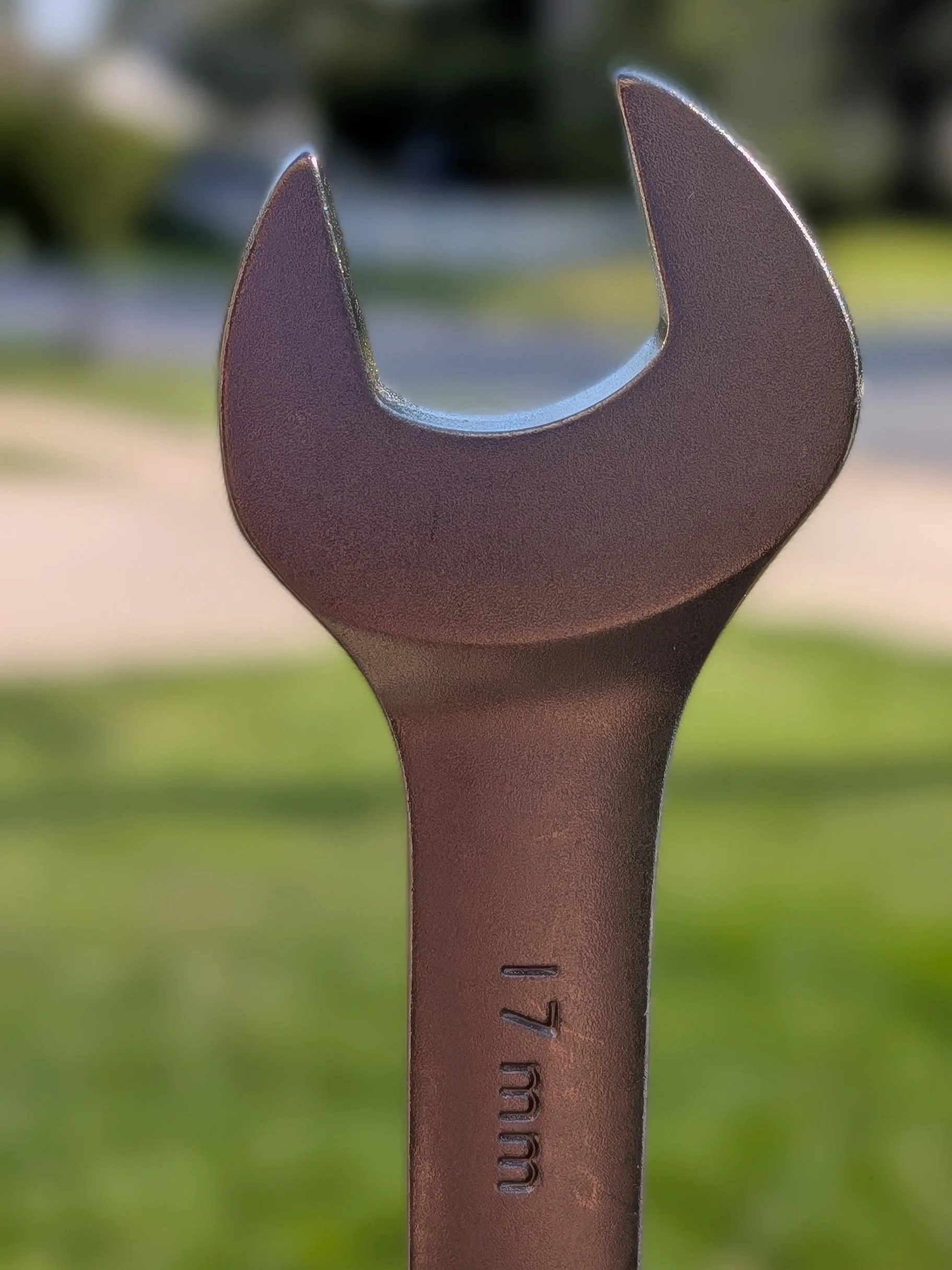 Close-up of a metal wrench for bicycle repair, outdoor garden background.