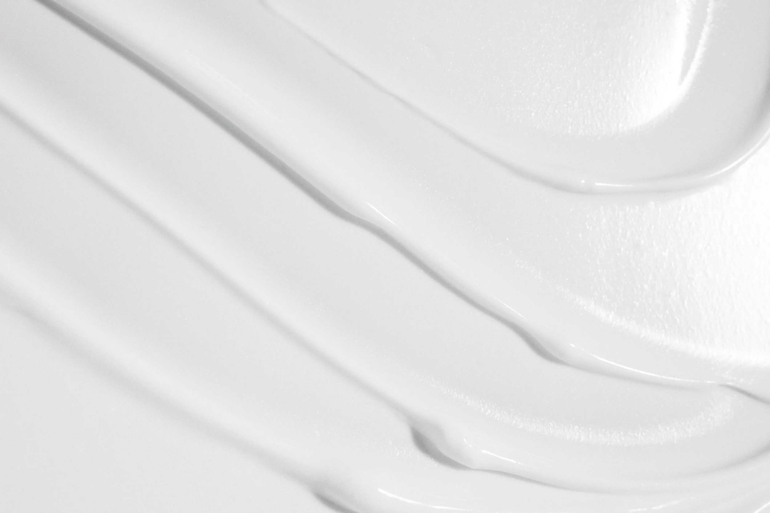Close-up of a white surface with a textured, rounded object partially visible in the top right corner.