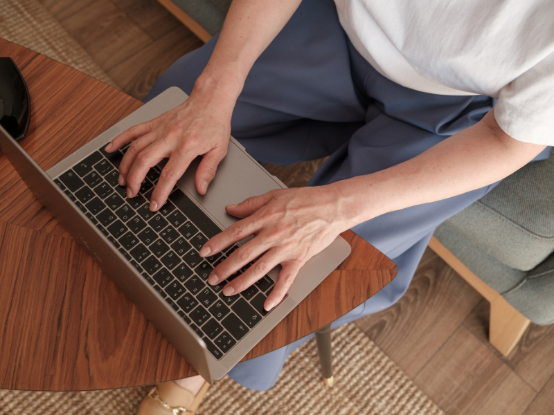 A person working on a laptop placed on a wooden table.