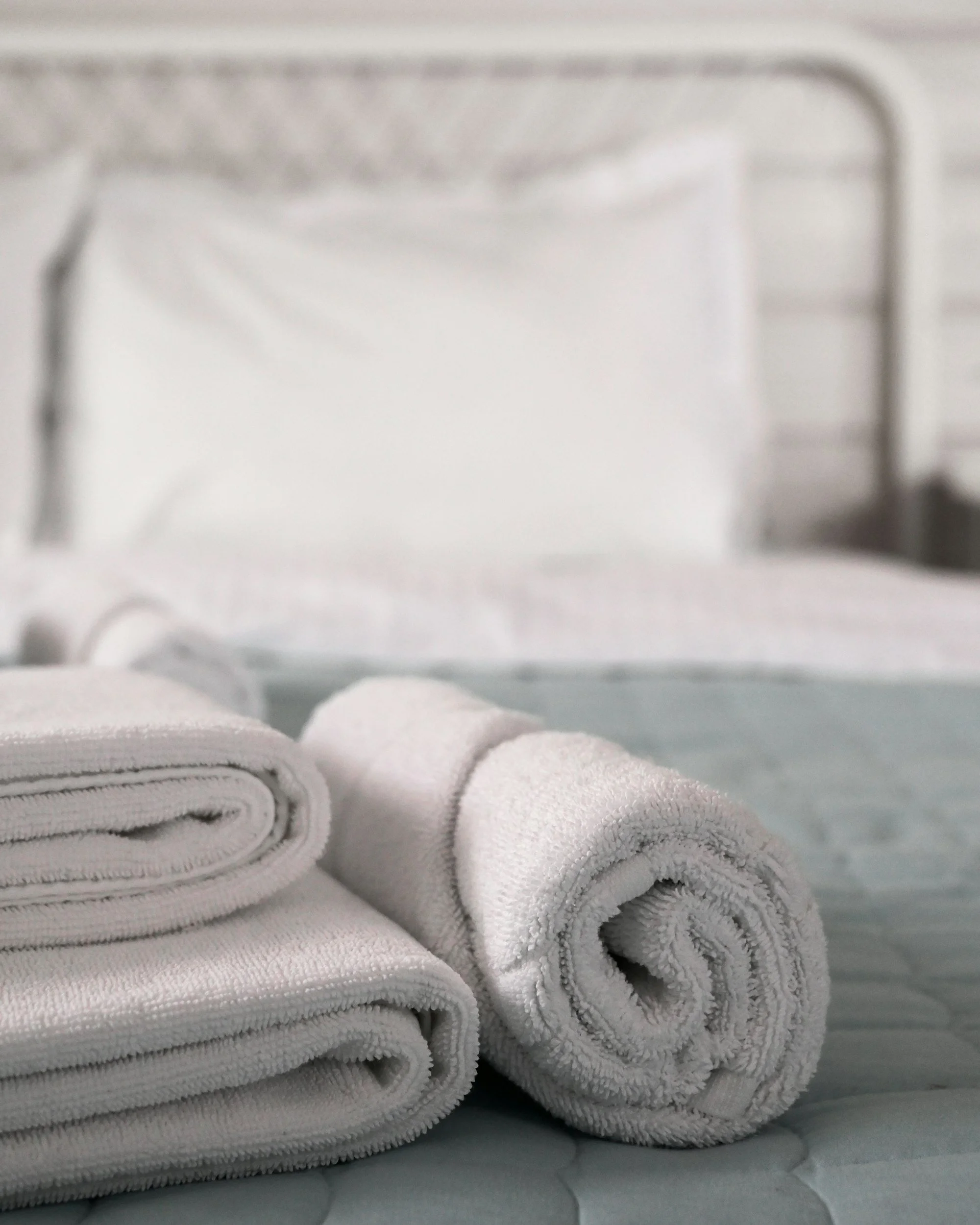 Stacked white towels on a surface, with a blurred background.