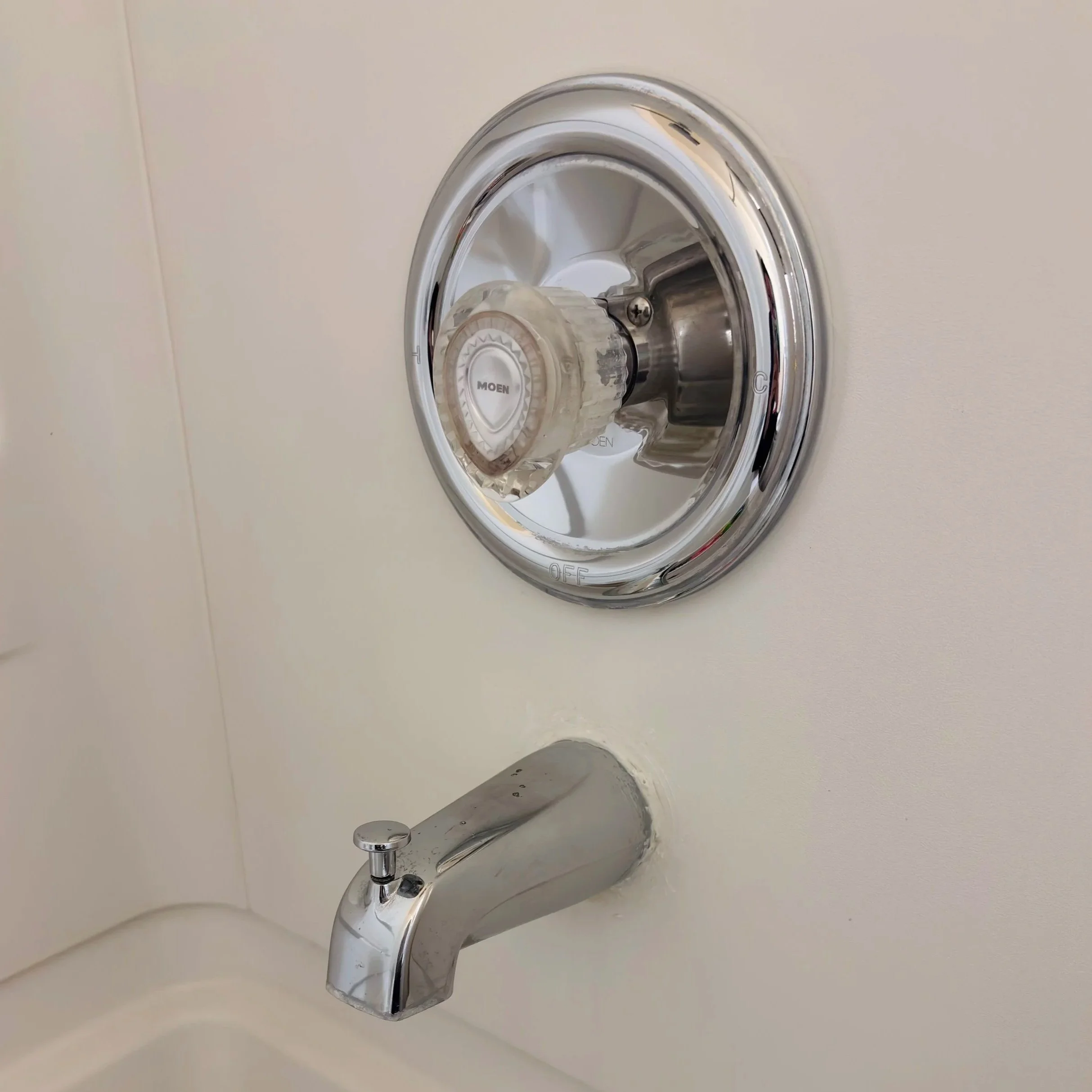 Close-up view of a silver kitchen faucet with a single handle installed on a light-colored sink and wall.