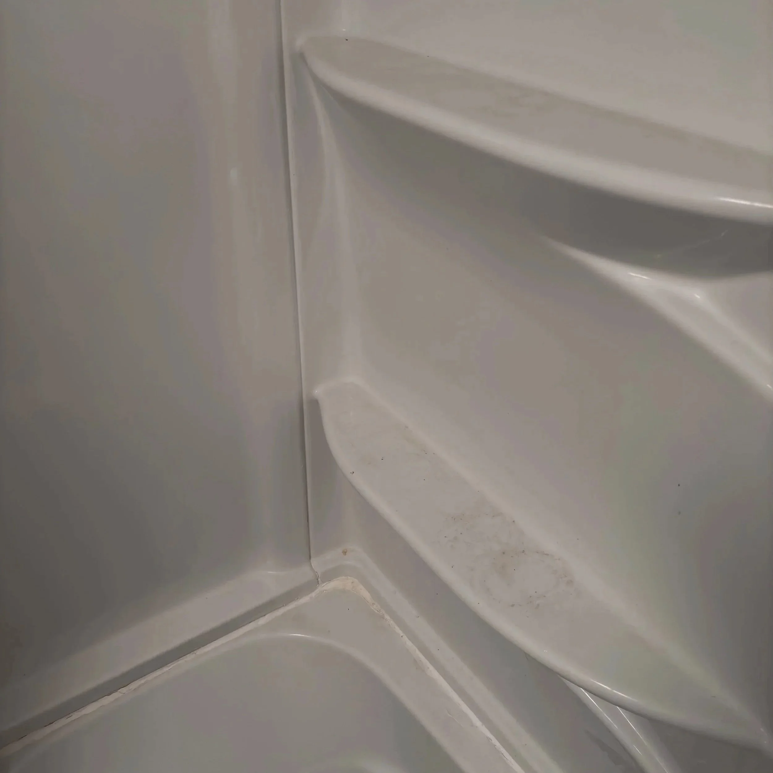 Close-up photo of a corner of a white toilet seat with the lid closed.