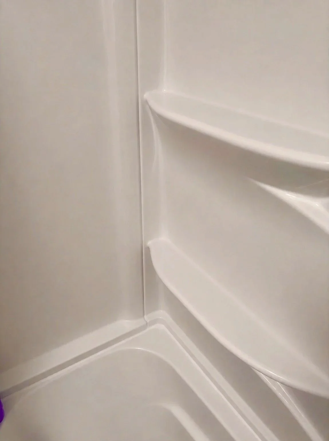 Inside a white shower enclosure with built-in shelves on the right side.